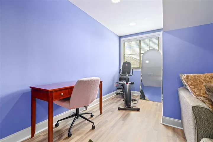 A flexible room ideal for a home office or fitness area, featuring LVP flooring and ample lighting.