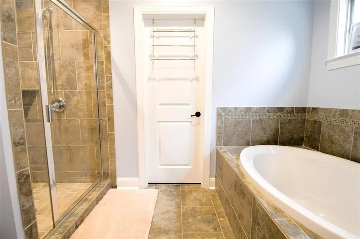 A well-appointed bathroom offers a glass-enclosed shower and a deep soaking tub, perfect for unwinding.