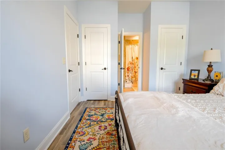 A comfortable bedroom with light-toned walls and durable wood flooring offers a private bath entrance.