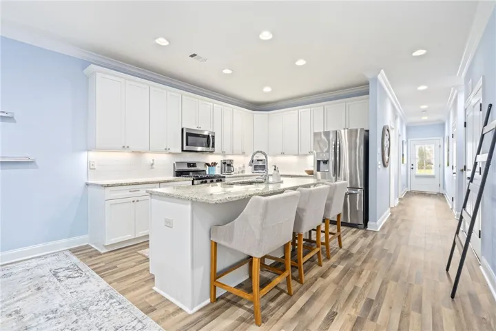 Culinary aspirations come alive in this kitchen, featuring white cabinetry and granite countertops, with ample space for dining at the island.