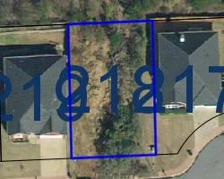 An aerial perspective showcases a spacious vacant lot, ready for development within a residential community.