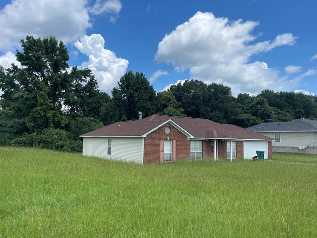 A classic brick and siding home with an attached garage, nestled amidst mature trees.
