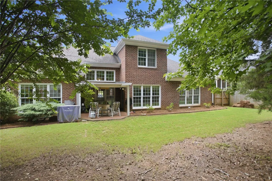 A spacious backyard with mature trees offers a private brick patio for outdoor living.