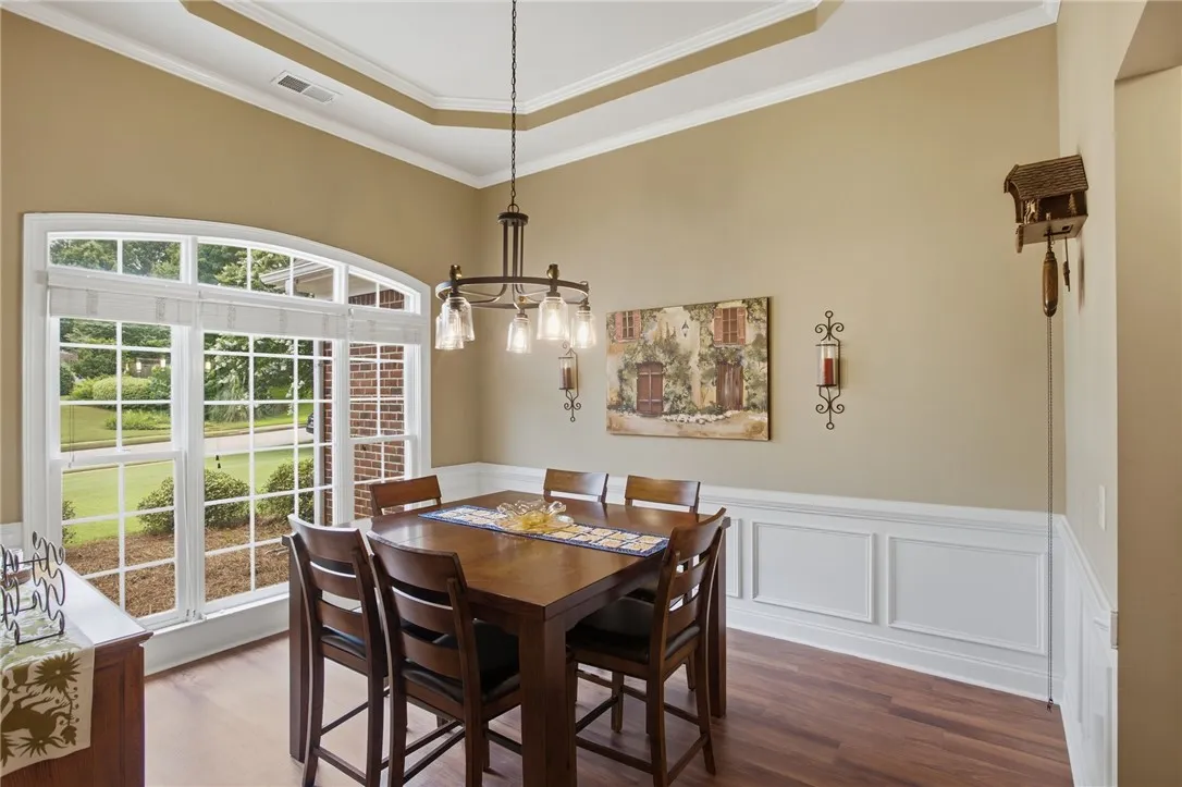 Features tray ceilings, rich wood flooring, and wainscoting.