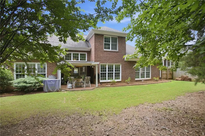 A spacious backyard with mature trees offers a private brick patio for outdoor living.