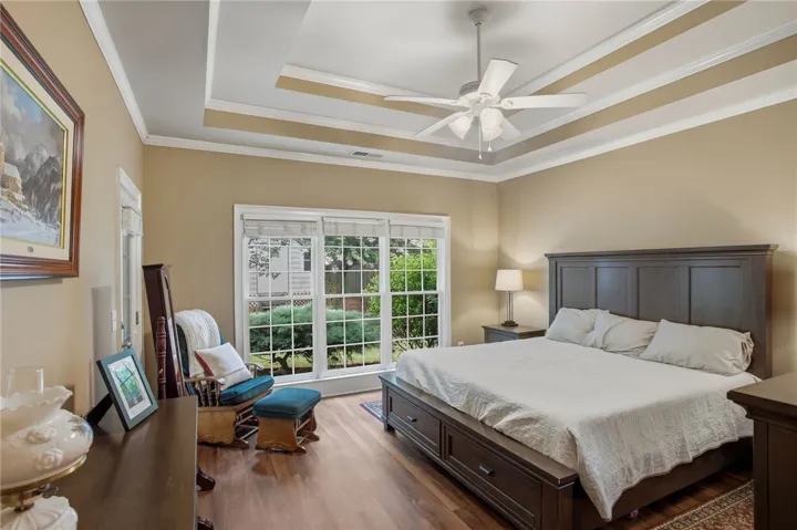 Hardwood floors and a stylish tray ceiling elevate this sunlit bedroom retreat.