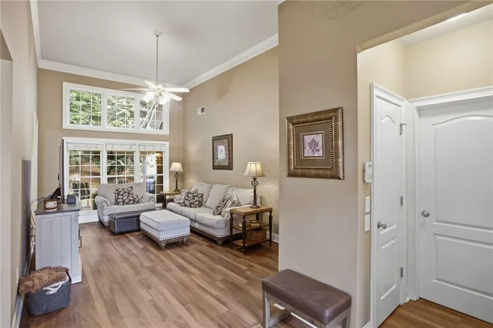 Well-lit living area featuring rich hardwood flooring and a towering ceiling.