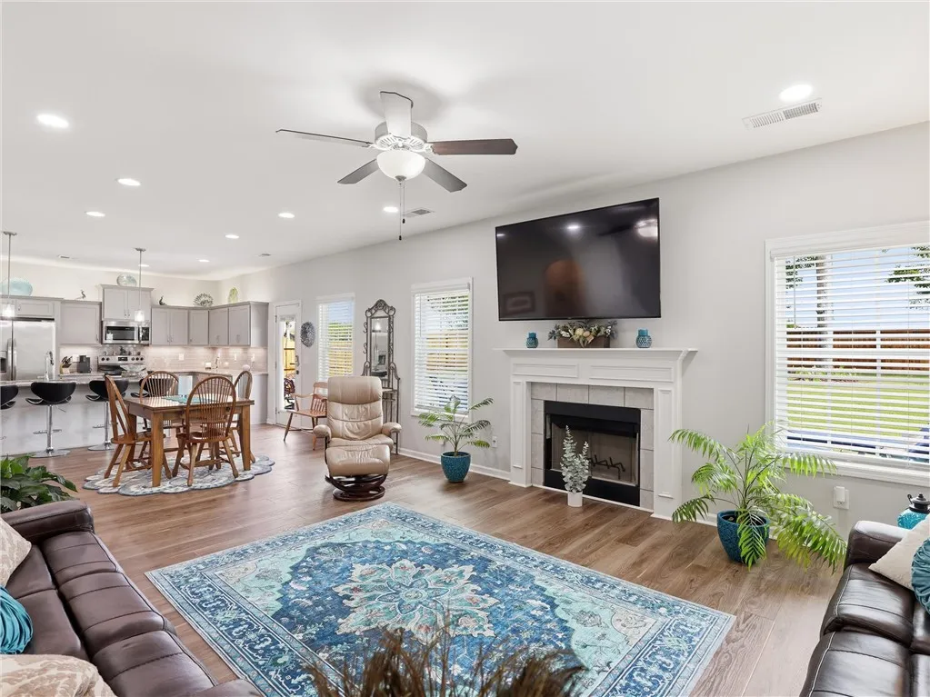 An open concept living area showcases hardwood floors, a cozy fireplace, and an adjoining kitchen.