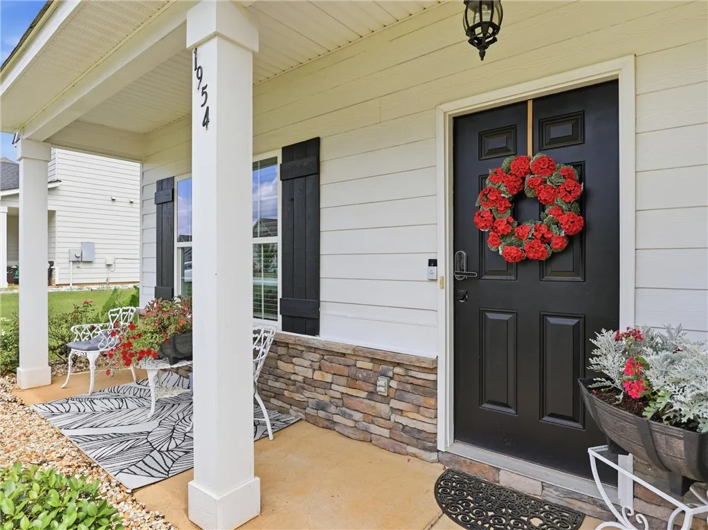 A welcoming front porch features a stylish black door, stone accents, and inviting outdoor seating.