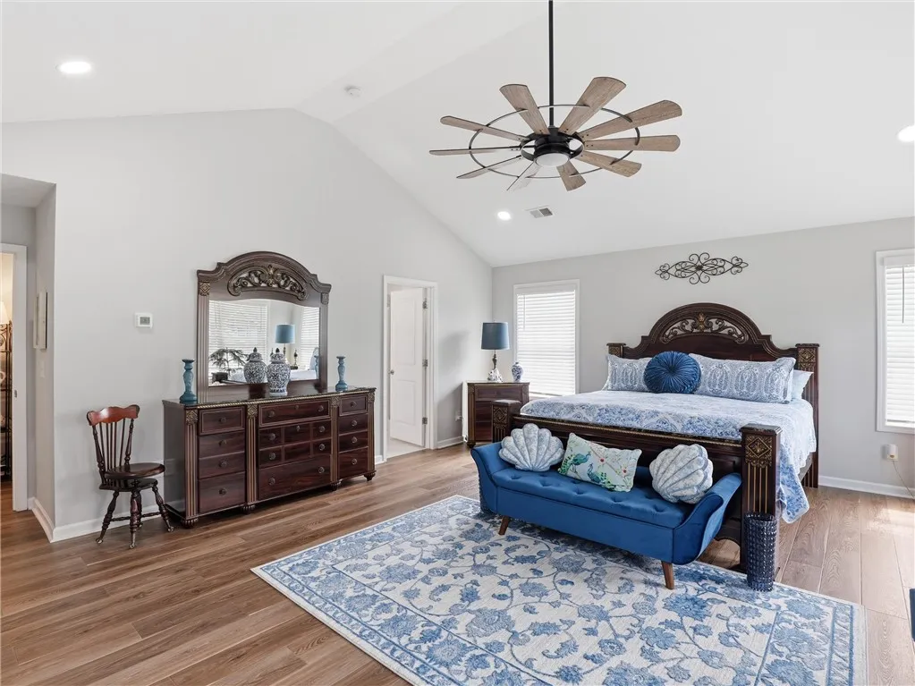 A vaulted ceiling and warm hardwood floors define this naturally illuminated primary bedroom.