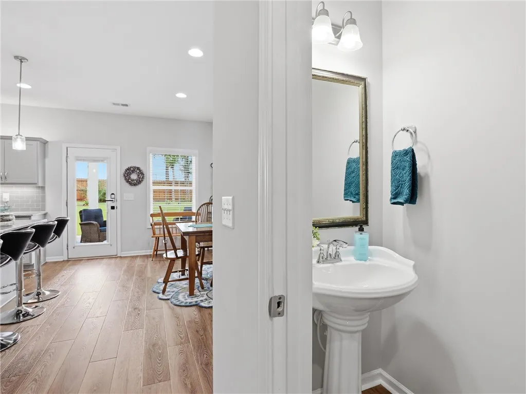 A well-appointed half bath features a pedestal sink and framed mirror, conveniently located near the dining area.