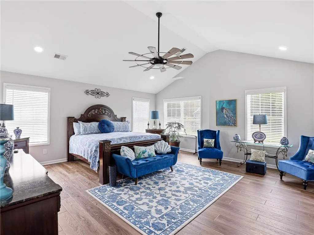 Hardwood floors and vaulted ceilings elevate this primary bedroom, offering both comfort and spaciousness.