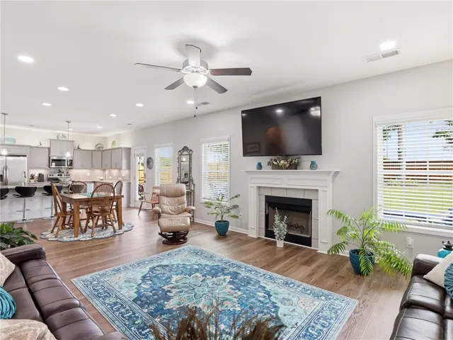 An open concept living area showcases hardwood floors, a cozy fireplace, and an adjoining kitchen.