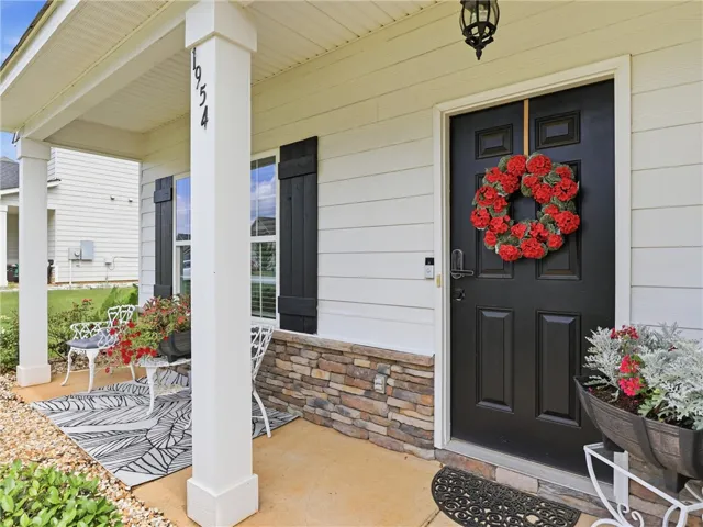 A welcoming front porch features a stylish black door, stone accents, and inviting outdoor seating.