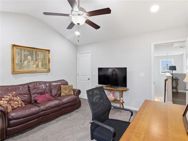 An inviting office space, complete with vaulted ceilings and a ceiling fan, offers comfort and functionality.