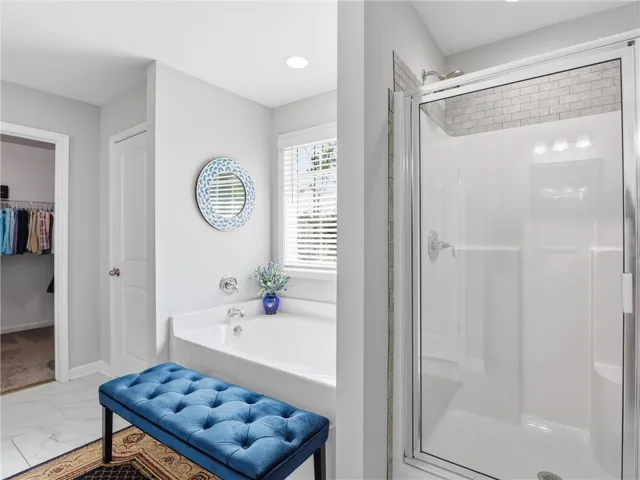 A well-lit bathroom showcases a spacious tub, a walk-in shower, and stylish tile flooring.