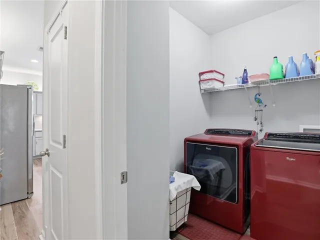 A well-appointed utility area features a full-size washer and dryer, complete with a convenient storage shelf above.