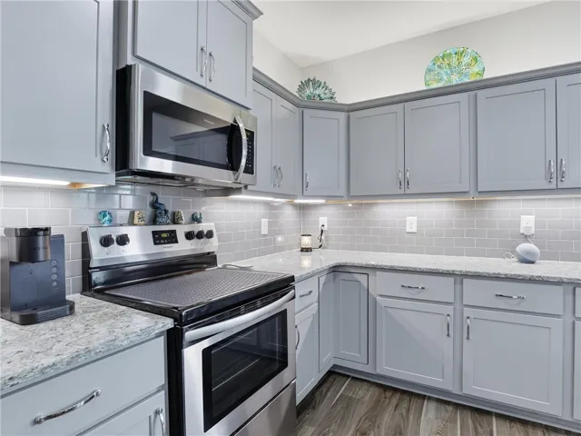 A contemporary kitchen showcasing sleek gray cabinetry, granite countertops, and modern stainless steel appliances.