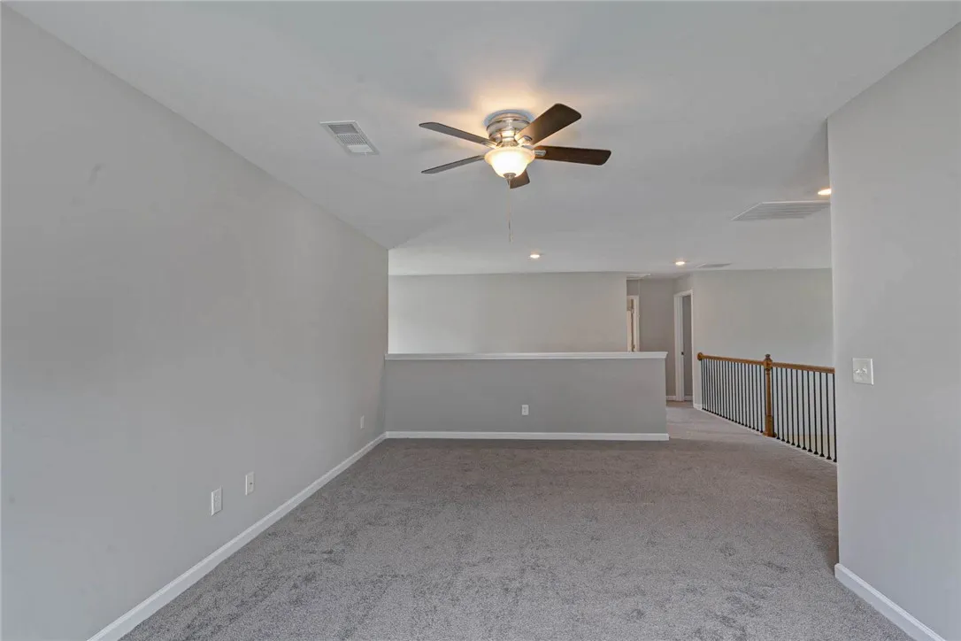 An inviting open loft space with plush carpeting and a modern ceiling fan for year-round comfort.