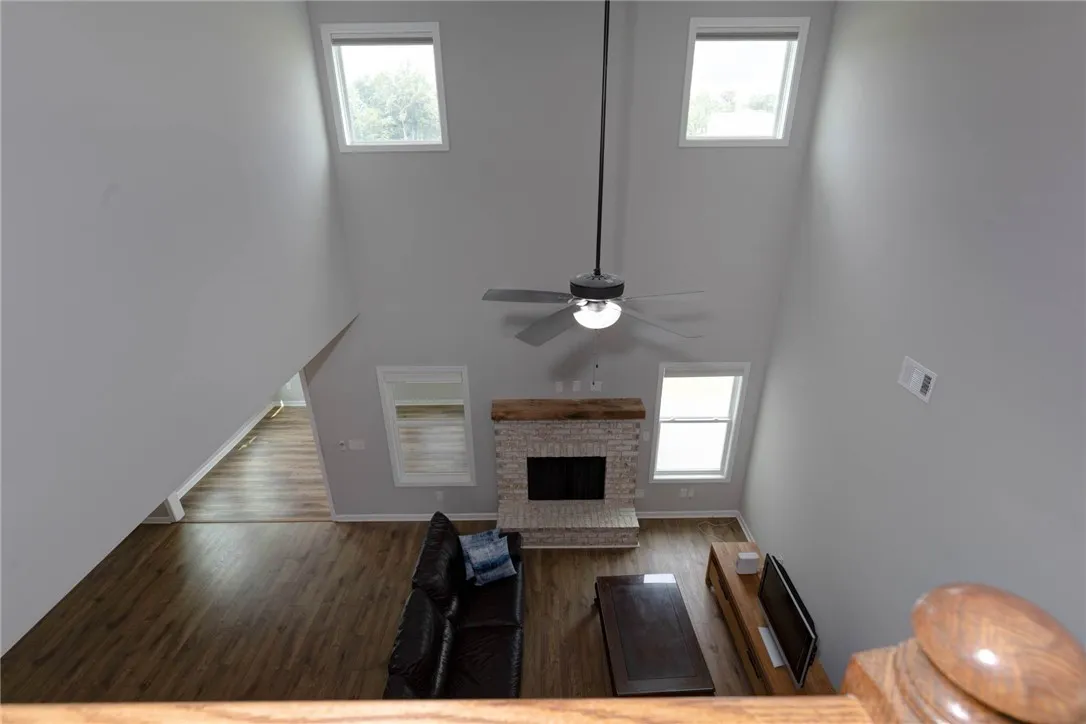 Dramatic vaulted ceilings create an airy atmosphere above rich wood flooring, centered by a charming brick fireplace.