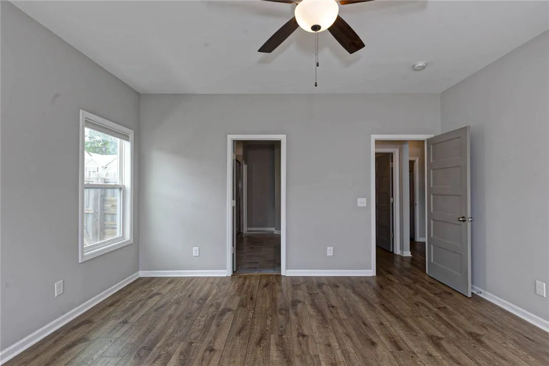A well-lit bedroom features rich wood flooring and a modern ceiling fan for ultimate comfort.