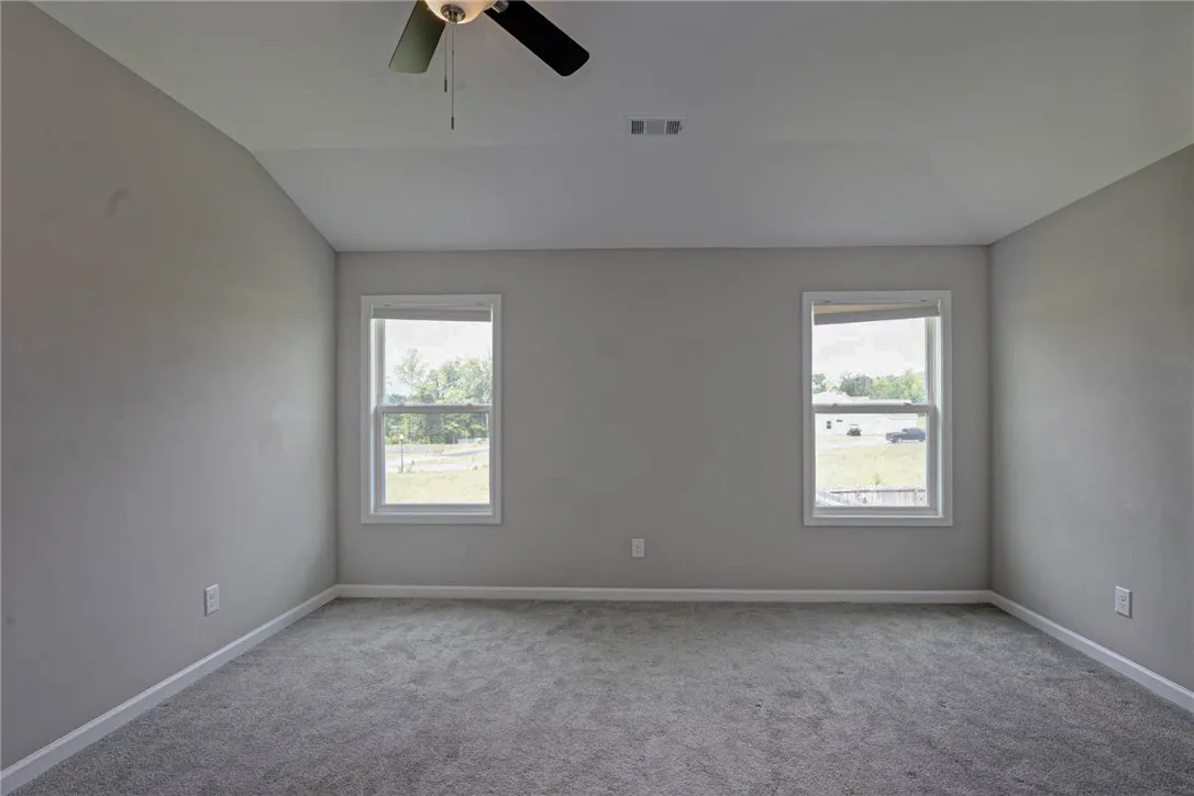 A quiet bedroom with twin windows and a ceiling fan, offering a tranquil retreat.