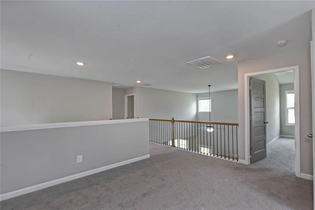 An airy loft area features neutral carpeting and bright recessed lighting.