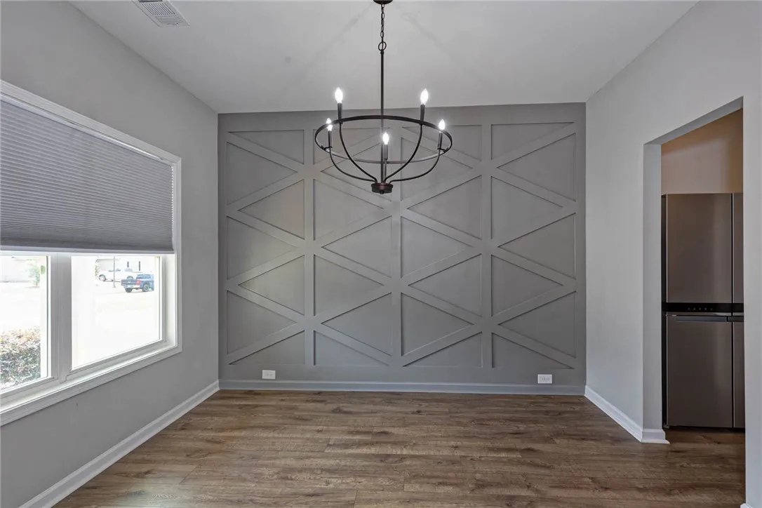 Artisan geometric accent wall and modern chandelier elevate this spacious dining area.