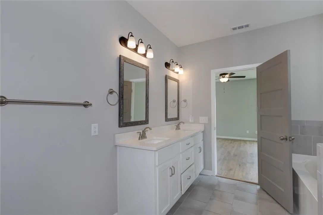 A well-appointed primary bathroom featuring a double vanity and a built-in tub.