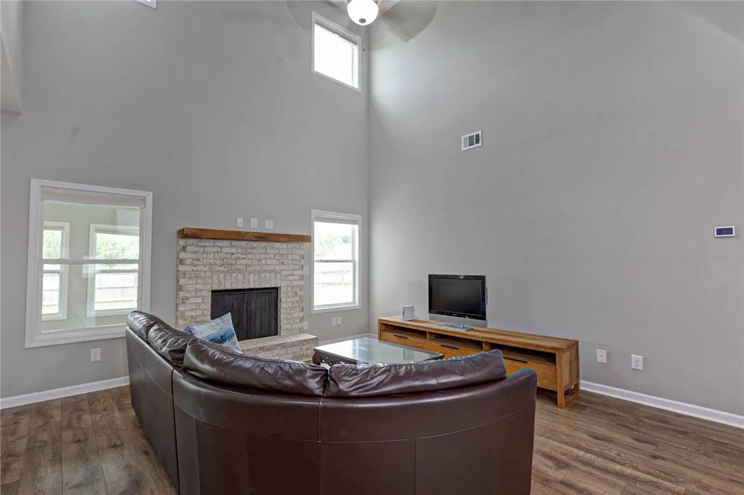 A spacious living area features high ceilings, a cozy fireplace, and rich wood flooring.