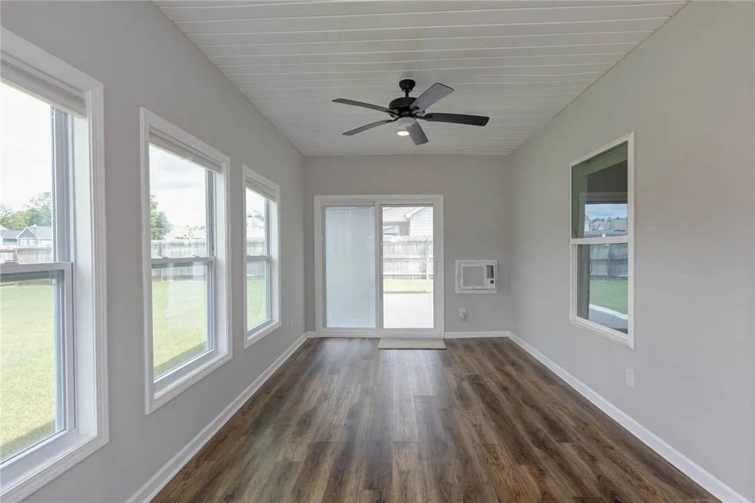 A bright sunroom with rich wood flooring and a refreshing ceiling fan invites relaxation and outdoor views.