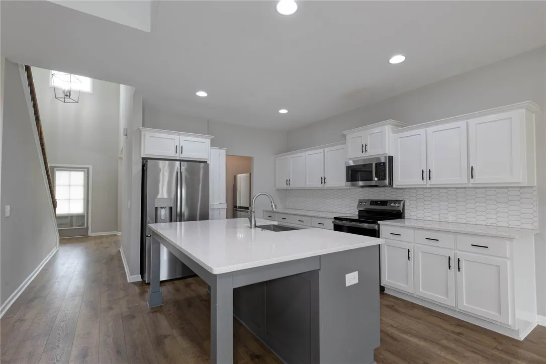 A contemporary kitchen features bright white cabinetry and a contrasting gray island, perfect for culinary endeavors.