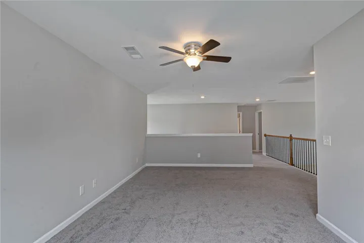 An inviting open loft space with plush carpeting and a modern ceiling fan for year-round comfort.