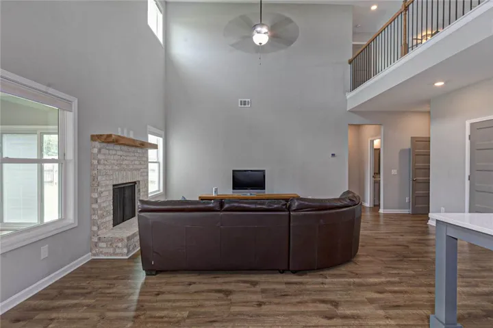 Two-story living area with hardwood floors and a white brick fireplace.