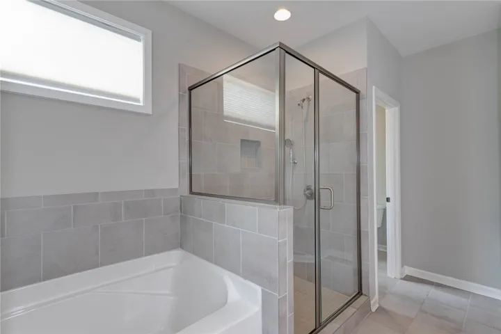 A well-appointed bathroom offers a separate soaking tub and a glass-enclosed shower.
