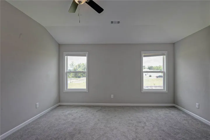 A quiet bedroom with twin windows and a ceiling fan, offering a tranquil retreat.