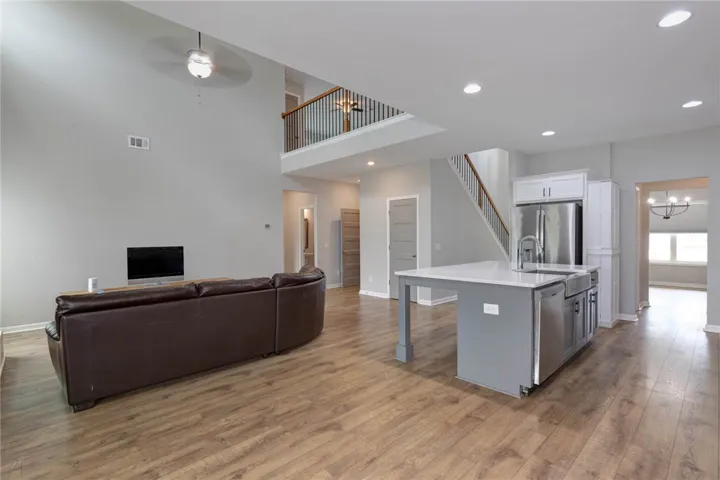 An open-concept living space presents high ceilings, a loft overlook, and a contemporary kitchen island.