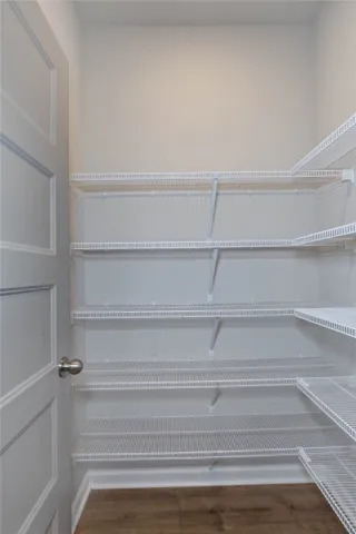 Well-organized pantry features wire shelving and durable flooring, ensuring ample storage.