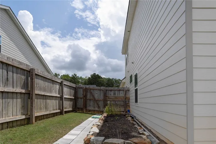 A private backyard oasis features a well-maintained wooden fence and a decorative stone-lined garden bed.