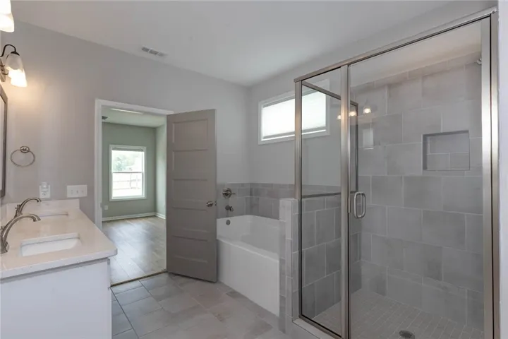 A well-appointed primary bathroom featuring a spacious shower and soaking tub, with a connecting door to an adjacent room.