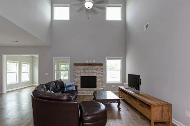 A spacious living area with soaring vaulted ceilings features a rustic brick fireplace and warm wood flooring.