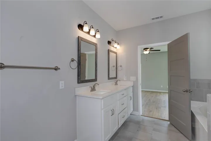 A well-appointed primary bathroom featuring a double vanity and a built-in tub.