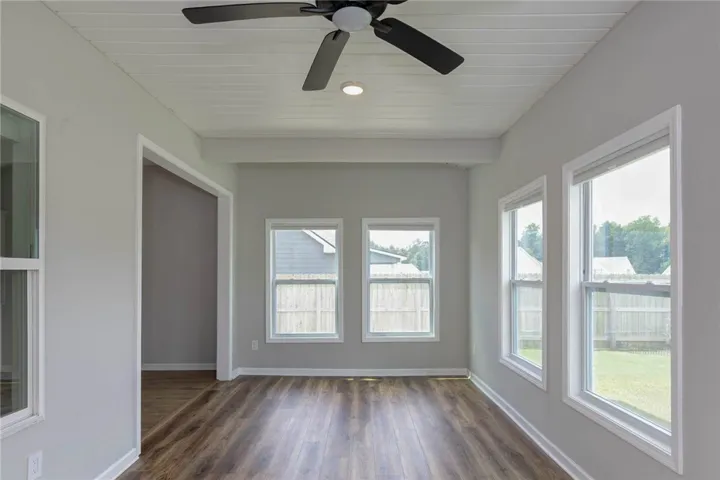 Hardwood-style flooring and multiple windows illuminate this adaptable space.