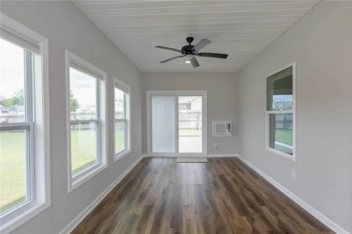 A bright sunroom with rich wood flooring and a refreshing ceiling fan invites relaxation and outdoor views.