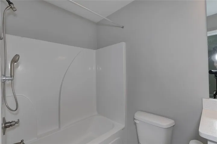 A well-maintained bathroom featuring a practical shower-tub combination and essential fixtures.