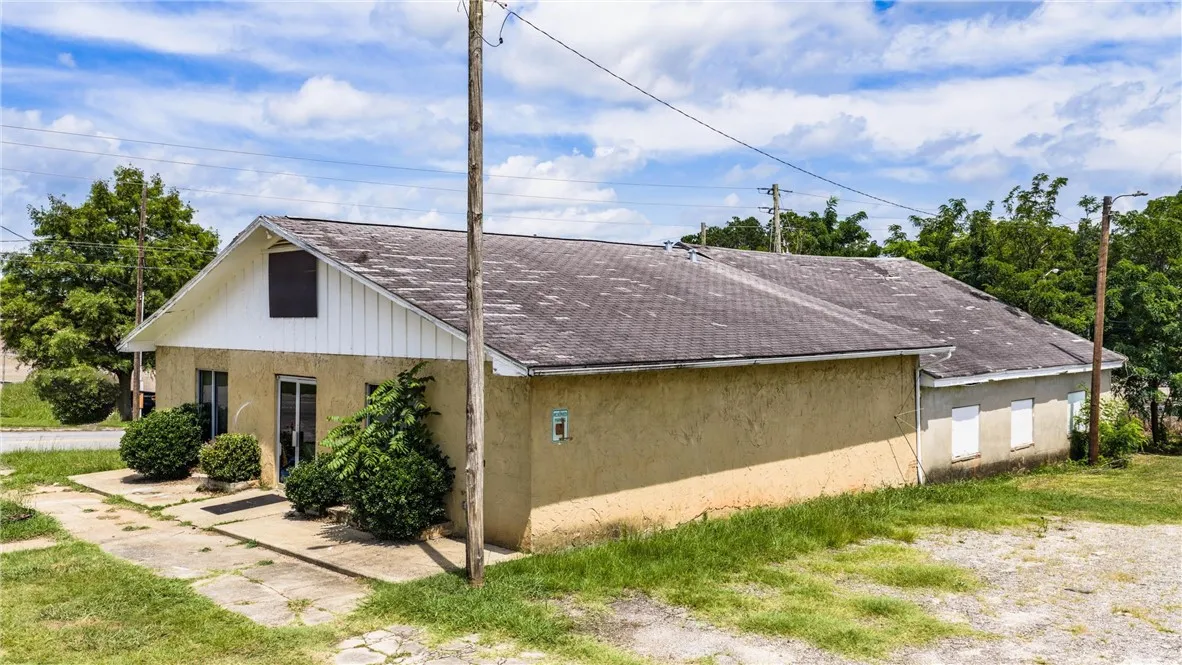 A modest stucco exterior with multiple windows and a gabled roof invites opportunity.