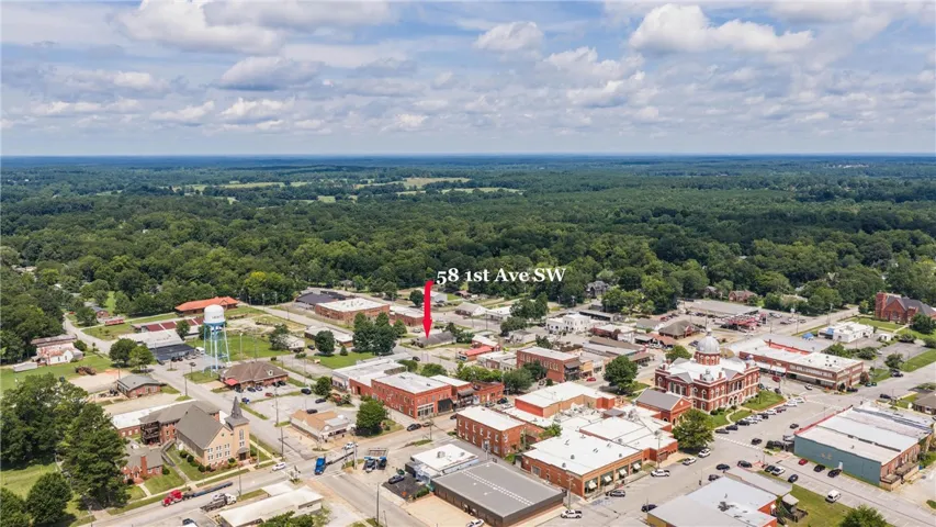 An aerial perspective reveals the property nestled within a vibrant downtown landscape, surrounded by verdant forests.