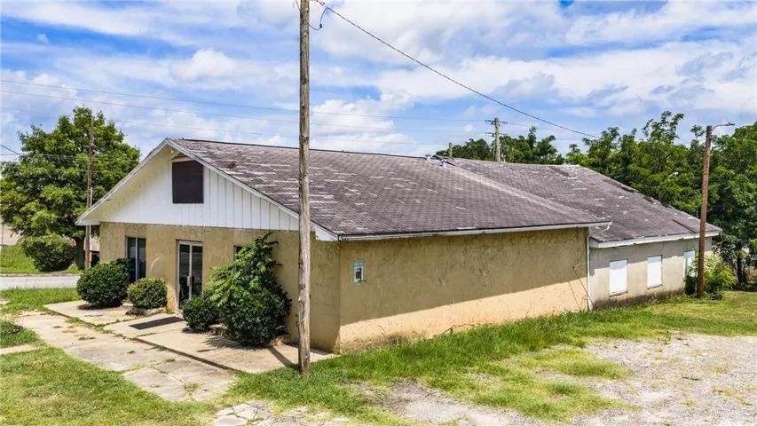 A modest stucco exterior with multiple windows and a gabled roof invites opportunity.