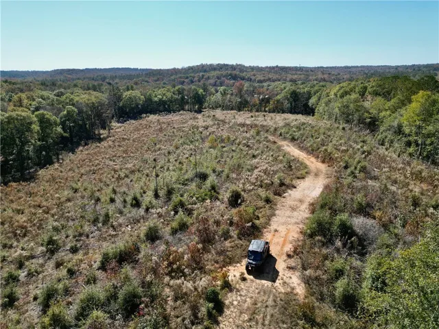 Vast acreage unfolds with a winding dirt path, leading through diverse natural landscapes.
