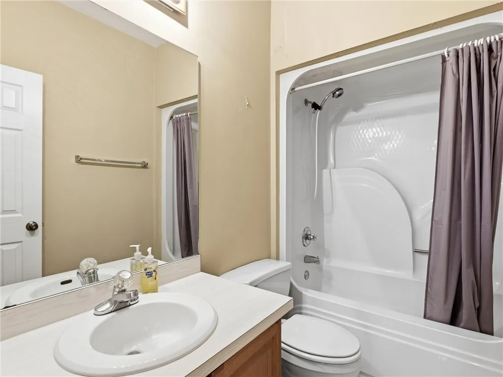 A well-maintained full bathroom presents a tub-shower combination and a vanity with an integrated sink.